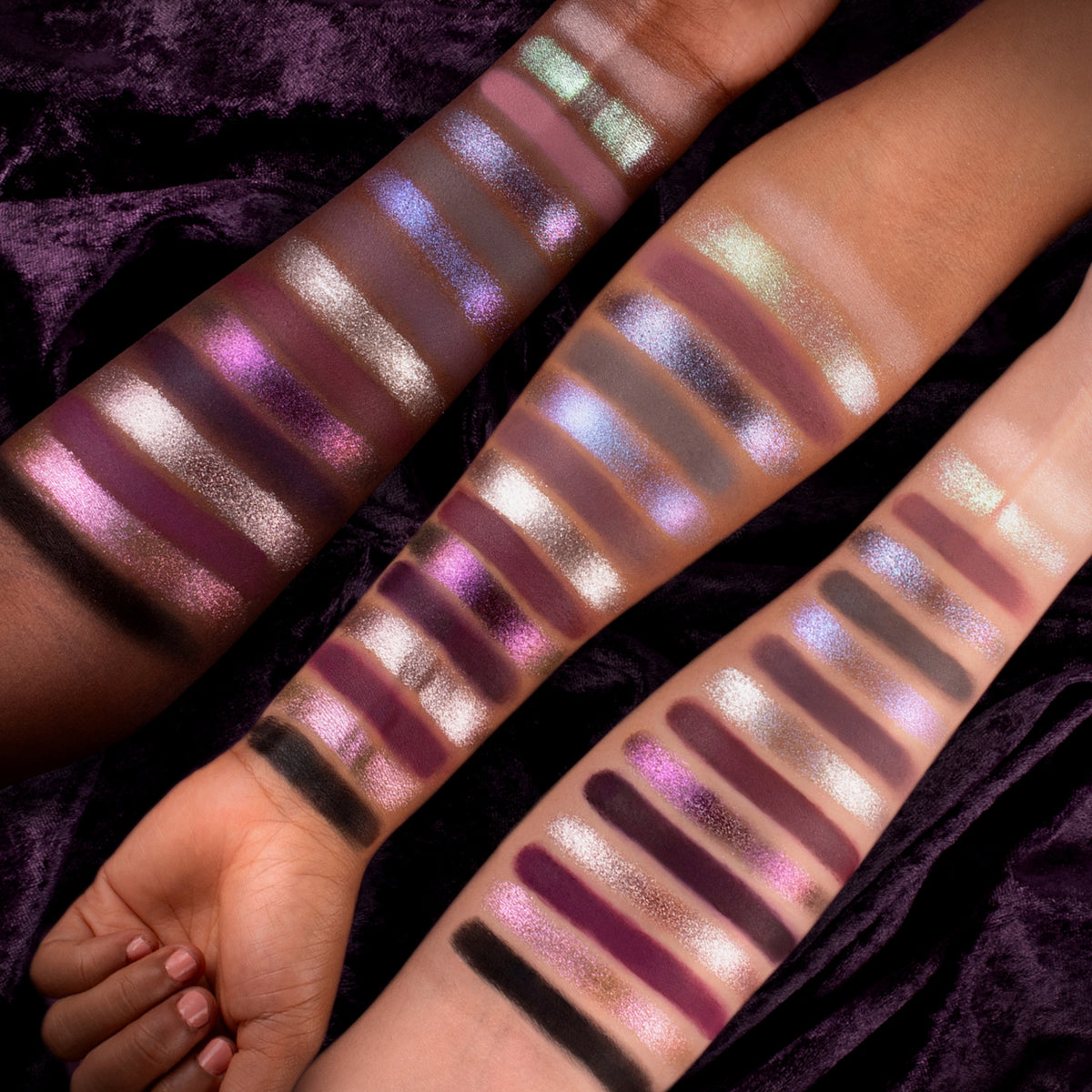 Drei Arme mit unterschiedlichen Hauttönen zeigen schimmernde violette, silberne und dunkle Lidschattenmuster aus der Spellcraft Pressed Powder Palette von Lethal Cosmetics.