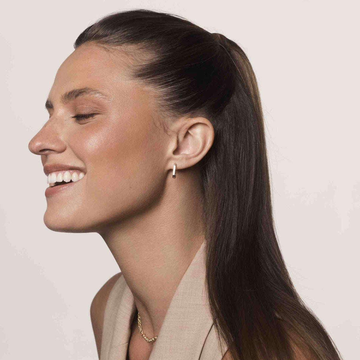 Eine Frau mit langem braunem Pferdeschwanz im Profil präsentiert den Effekt der Living Proof No Frizz Smooth Styling Cream.