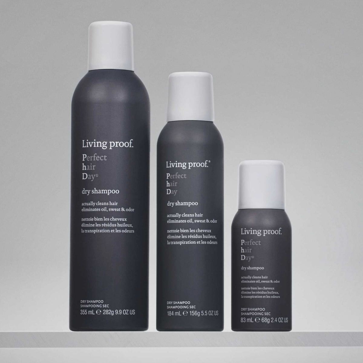 Auf grauem Hintergrund sind drei Flaschen Living Proof Perfect Hair Day Dry Shampoo in unterschiedlichen Größen abgebildet.
