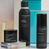 Living Proof Style Lab Flex Hairspray neben weiteren Styling Produkten vor lebendigen geometrischen Formen.