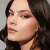 Eine Frau mit braunen Haaren und Smokey-Eye-Make-up aus der ARCHETYPE II Palette blickt vor neutralem Hintergrund in die Kamera.