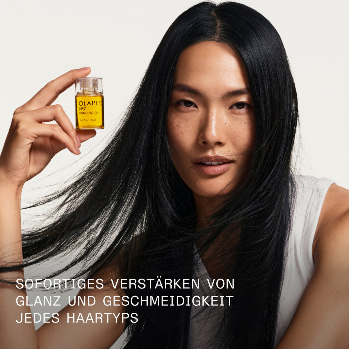 Eine Frau mit langem schwarzem Haar hält eine Flasche N°7 Bonding Oil 30ml; das für mehr Glanz und Geschmeidigkeit sorgt.