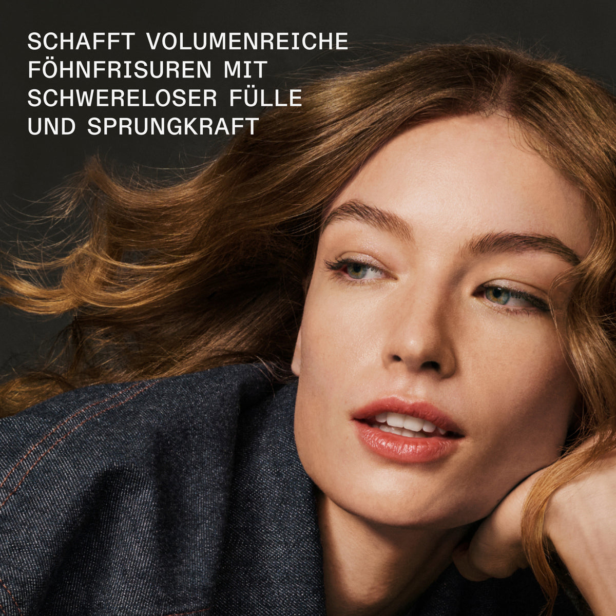 Eine Frau mit karamellblondem wehendem Haar schaut zur Seite; dazu Text: "schafft volumenreiche Föhnfrisuren mit schwereloser Fülle und Sprungkraft."