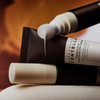 Dunkle Tube der SKIN1004 Centella Eye Cream mit hellem Aufdruck, geöffnet; cremige Textur tritt aus der Spitze aus, Hintergrund in warmen Orangetönen.