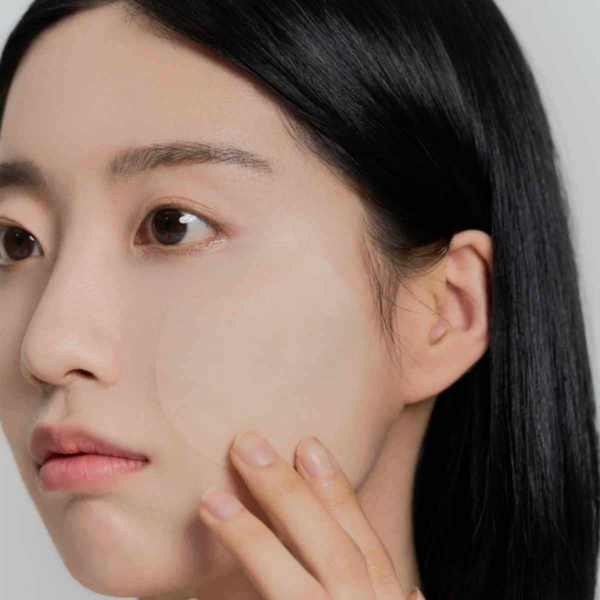 Eine Frau trägt das SKIN1004 Madagascar Centella Quick Calming Pad mit ihren Fingern auf ihre Wange auf.