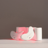 Zwei weiße, bohnenförmige STYLPRO LED Patch Duo-Geräte mit rotem Licht stehen auf einem geschwungenen Ständer vor einem schlichten Hintergrund.