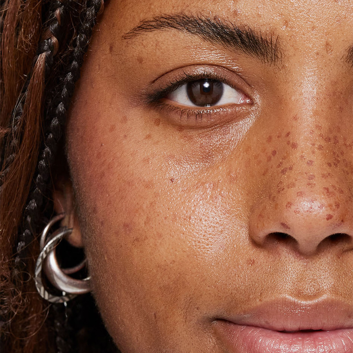 Nahaufnahme eines Auges und einer Wange mit sichtbaren Wimpern, die durch den XLASH Lash Booster betont werden.
