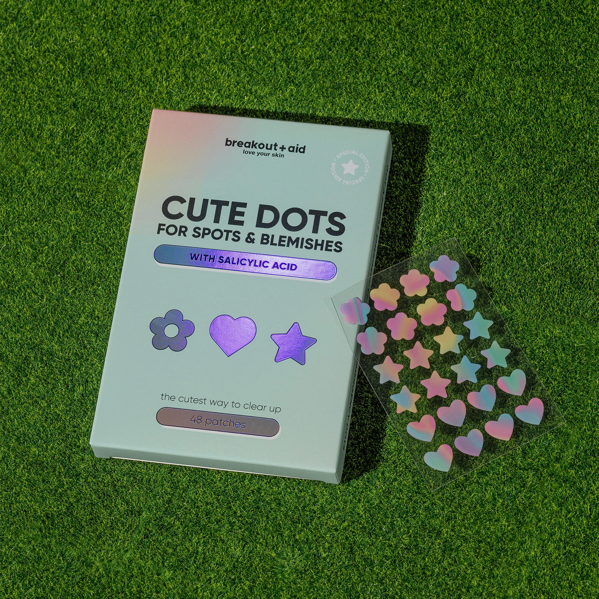 Cute Dots for Spots & Blemishes – Akne-Pflaster in Blumen-, Herz- und Sternform, dazu ein transparentes Blatt mit passenden, schillernden Aufklebern.