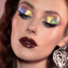 Frau mit dramatischem Eyeliner und glänzenden dunkelroten Lippen trägt gelb, grün und lila schimmernden Opal Moonstone Loose Multichrome Eyeshadow in Cry Baby auf den Augen.