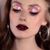 Frau mit dramatischem Eyeliner und glänzenden dunkelroten Lippen trägt rosa schimmernden Opal Moonstone Loose Multichrome Eyeshadow in Drama Queen auf den Augen.