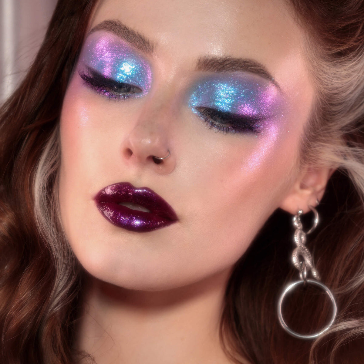 Frau mit dramatischem Eyeliner und glänzenden dunkelroten Lippen trägt lila-blau schimmernden Opal Moonstone Loose Multichrome Eyeshadow in Lazy Bones auf den Augen.
