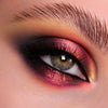 Nahaufnahme eines Auges mit dramatischem Eyeliner und rot-orange schimmerndem Opal Multichrome Loose Eyeshadow in Pillow Fight.