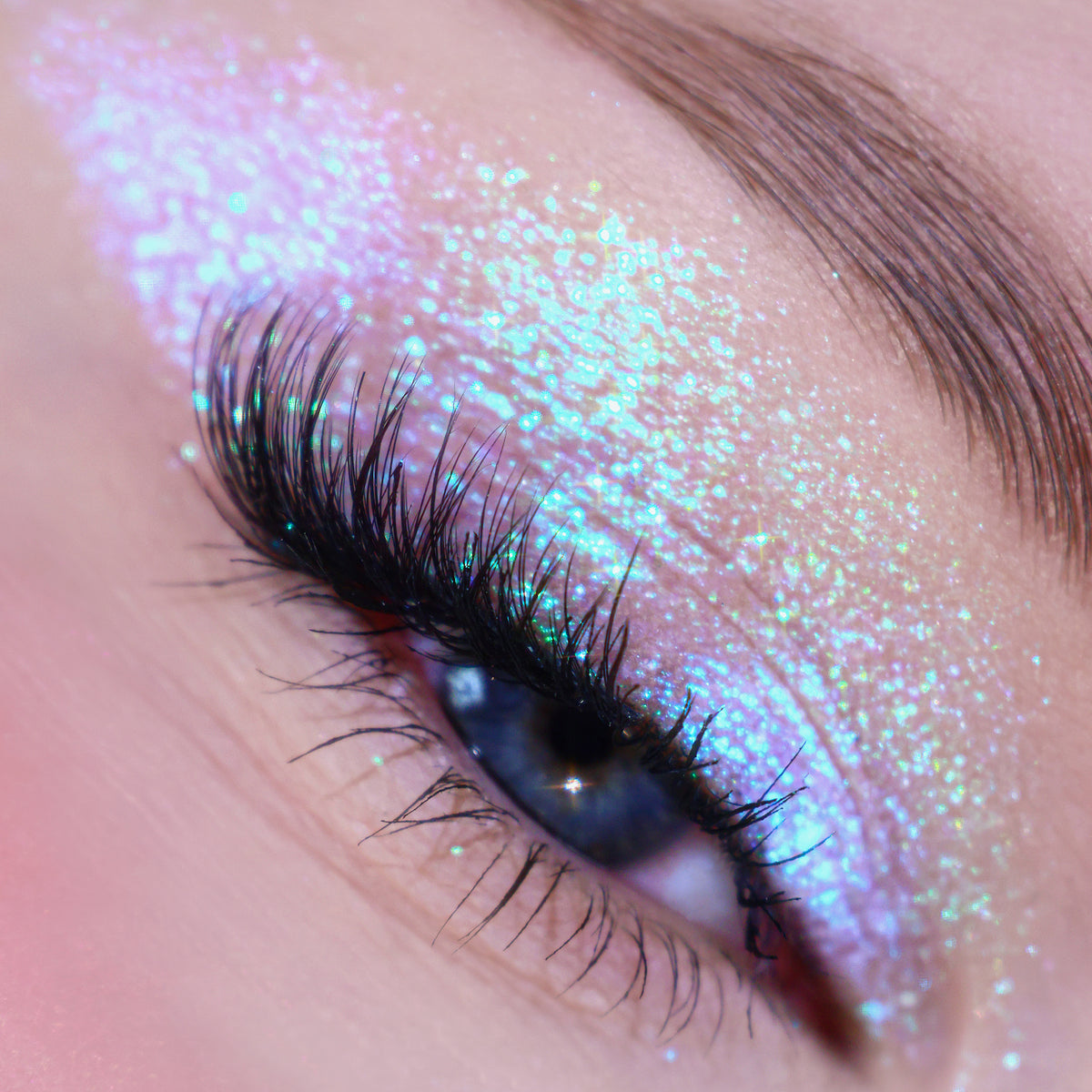 Nahaufnahme eines Auges mit dramatischem Eyeliner und lila-blau schimmerndem Pressed Opal Multichrome Eyeshadow in Birdsong.
