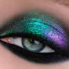 Eine Nahaufnahme eines Auges zeigt kräftigen, schimmernden grünen und violetten Lidschatten über Shadow Potion Paint Black Base Eclipse, abgerundet mit einem dramatischen schwarzen Eyeliner.