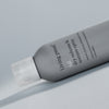 Eine Flasche Living Proof Full Dry Volume & Texture Spray in Grau steht auf einer hellen Oberfläche.