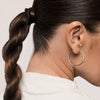 Eine Frau mit einem gedrehten Pferdeschwanz präsentiert glattes Haar, das mit Living Proof No Frizz Smooth Styling Spray gestylt wurde.