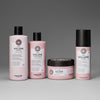 Vier rosane maria nila Pure Volume Haarprodukte: Shampoo, Spülung, Maske und Pure Volume Mousse vor grauem Hintergrund.
