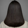 Eine Person mit glattem, glänzendem, dunkelbraunem Haar, von hinten, zeigt das Ergebnis der Anwendung von maria nila's True Soft Shampoo.