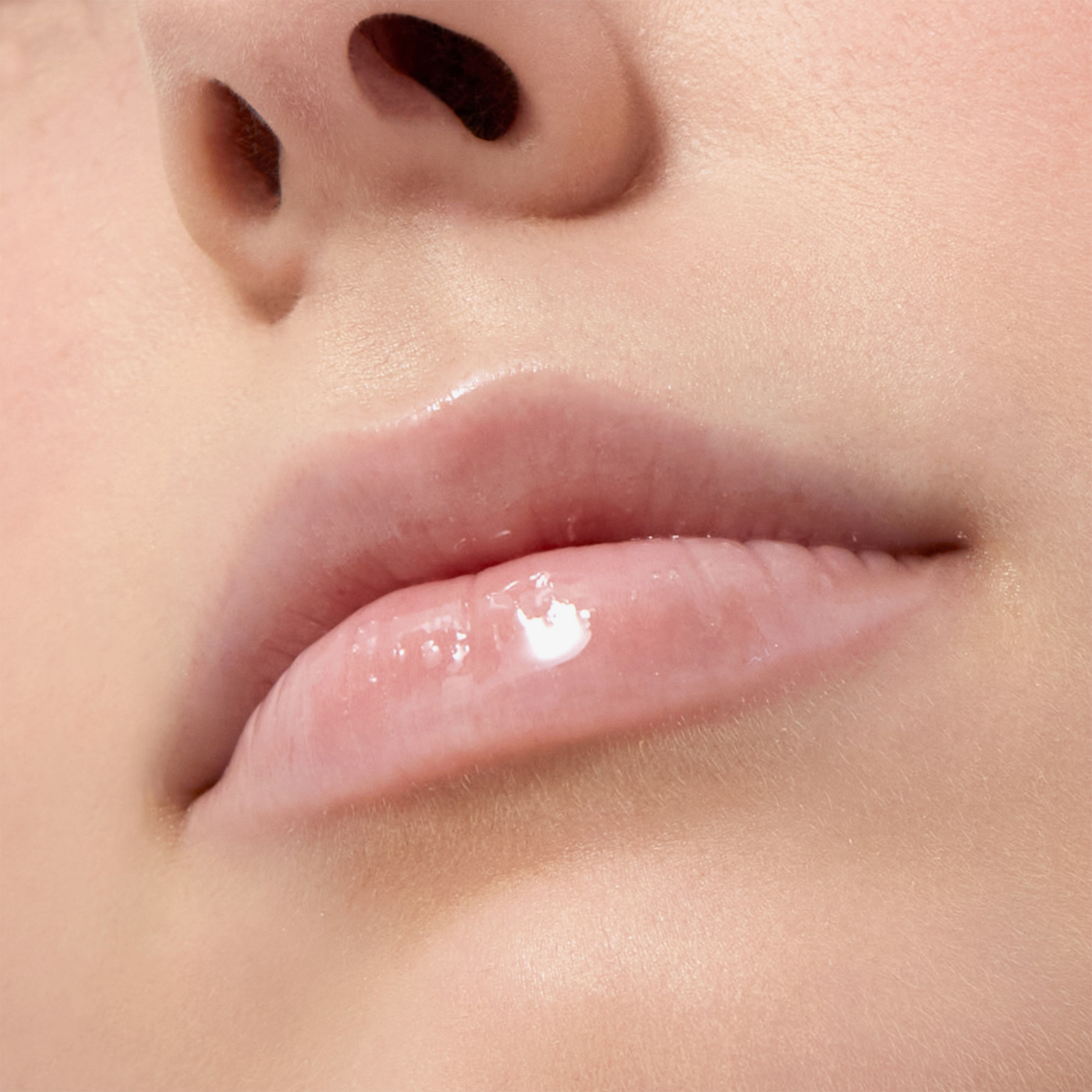 Nahaufnahme von Lippen, auf denen ein transparenter, glänzender Lippenbalsam aus dem COSMIC KISS CHRISTMAS KIT aufgetragen ist.