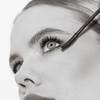 Schwarz-Weiß-Nahaufnahme einer Frau, die THE GLAM FEMULINE Mascara von Mesauda Beauty mit einem Zauberstab auf ihre Wimpern aufträgt.