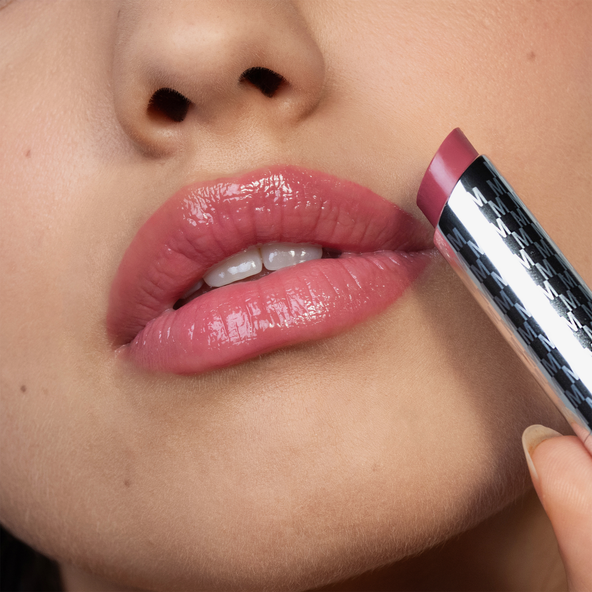 Nahaufnahme einer Person, die das THE HYDRAMORPHOSIS TWIN SET von Mesauda Beauty aufträgt, wobei die glatte Haut und die glänzende rosa Lippenfarbe des Sets hervorgehoben werden.