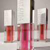 Drei Flaschen Mesauda Beauty LIPOILOGY™ Lipgloss mit silbernen Kappen, in verschiedenen Tönen auf einer weißen Fläche.