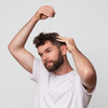 Ein Mann mit weißem T-Shirt trägt Scandinavian Biolabs Bio Plixin Serum+ Men mit einer Pipette auf seine Kopfhaut auf.