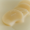 Mehrere beige Pads in Nierenform, durchtränkt mit Flüssigkeit. Obenauf liegt eine transparente Pinzette zur hygienischen Entnahme der Pads.
