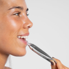 Eine Frau trägt vor einem schlichten Hintergrund die Volume Hydrating Lip-Plumping Treatment auf ihre Lippen auf.