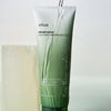 Eine Tube Heartleaf LHA Moisture Peeling Gel, über die Wasser gegossen wird, neben einem weißen rechteckigen Block.
