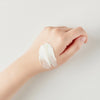 Eine Hand mit einem Klecks Seven Layer Ceramide Cream auf dem Handrücken vor einem schlichten hellen Hintergrund.