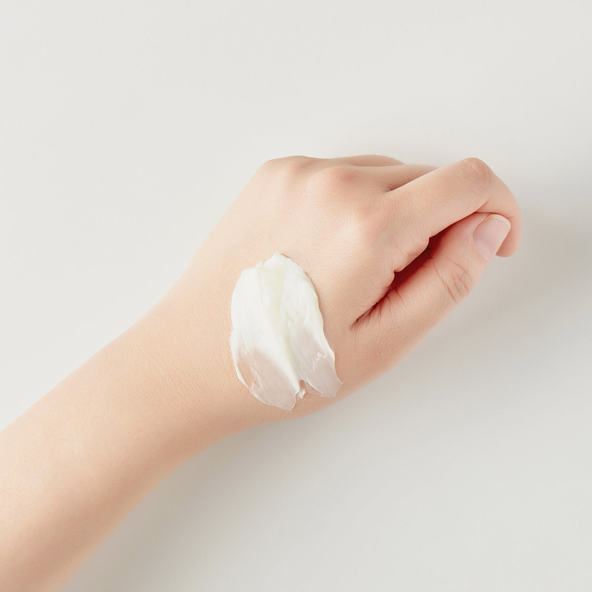 Eine Hand mit einem Klecks Seven Layer Ceramide Cream auf dem Handrücken vor einem schlichten hellen Hintergrund.