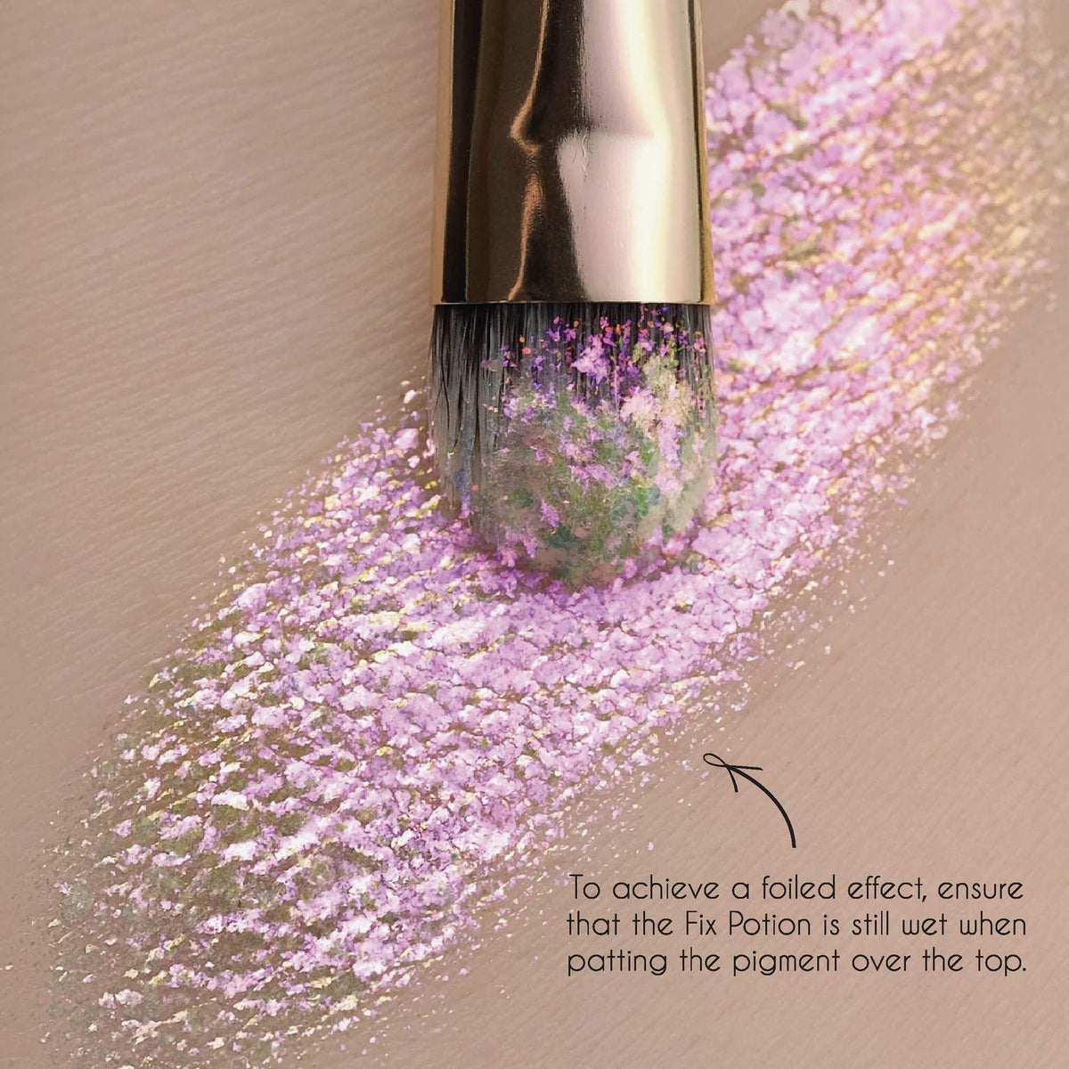 Ein Pinsel trägt schimmerndes rosa Pigment auf die, mit der Fix Potion preparierte Haut auf.