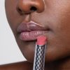Nahaufnahme von glänzenden Lippen und dem rosa Lippenstift THE HYDRAMORPHOSIS TWIN SET von Mesauda Beauty in einer Metalltube, der in der Nähe des Mundes gehalten wird.