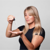 Eine Frau mit langen blonden Haaren trägt vor einem grauen Hintergrund Bio-Pilixin® Serum+ Women von Scandinavian Biolabs auf ihre Handfläche auf.