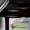 Eine Nahaufnahme eines geöffneten Tiegels mit der Aufschrift Firm Hybrid Clay von Scandinavian Biolabs, auf dem Creme verschmiert ist.