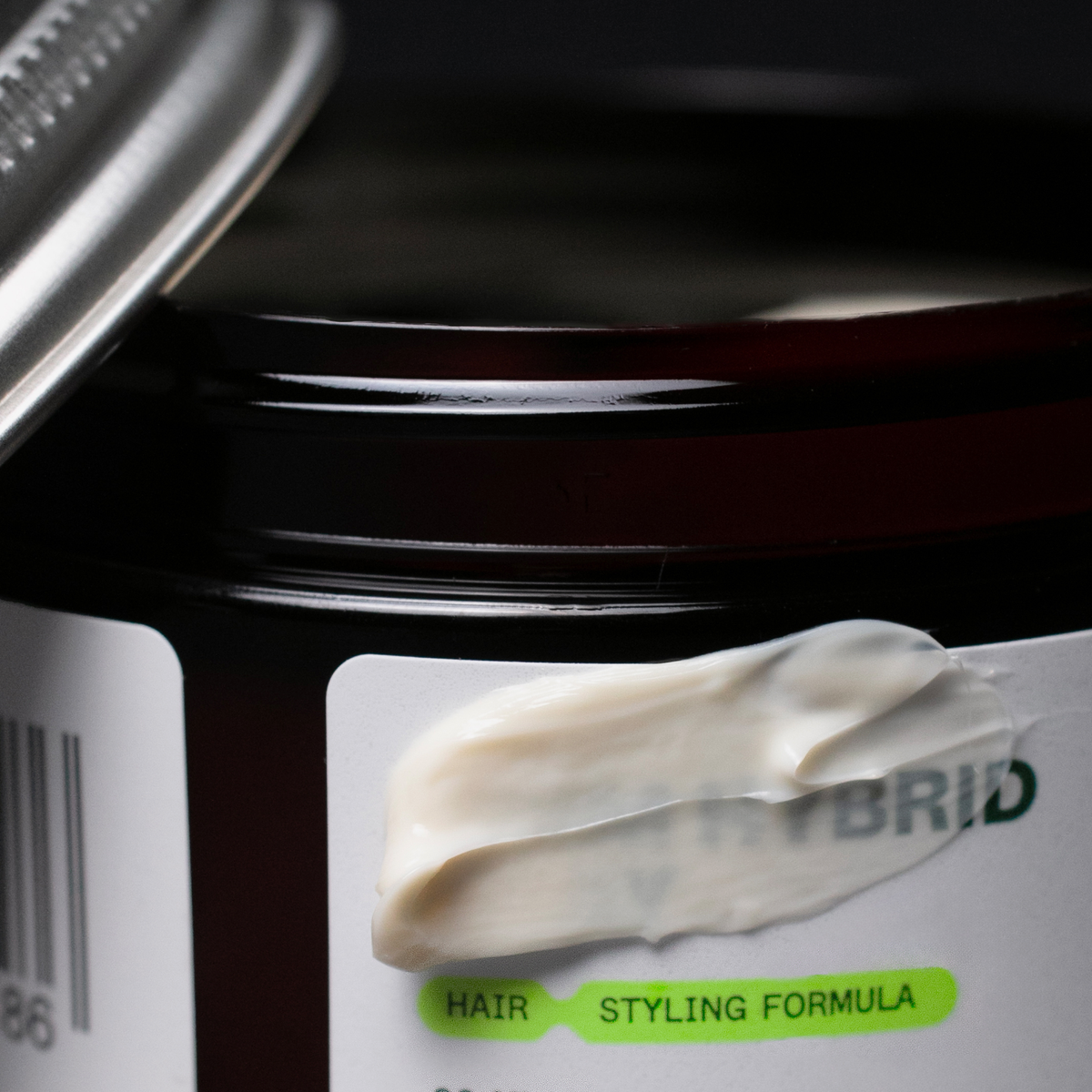 Eine Nahaufnahme eines geöffneten Tiegels mit der Aufschrift Firm Hybrid Clay von Scandinavian Biolabs, auf dem Creme verschmiert ist.
