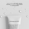 Eine Cremetube mit Niacinamide Glow Cream ist von Wassertropfen auf grauem Hintergrund umgeben und hebt die Produkteigenschaften hervor.