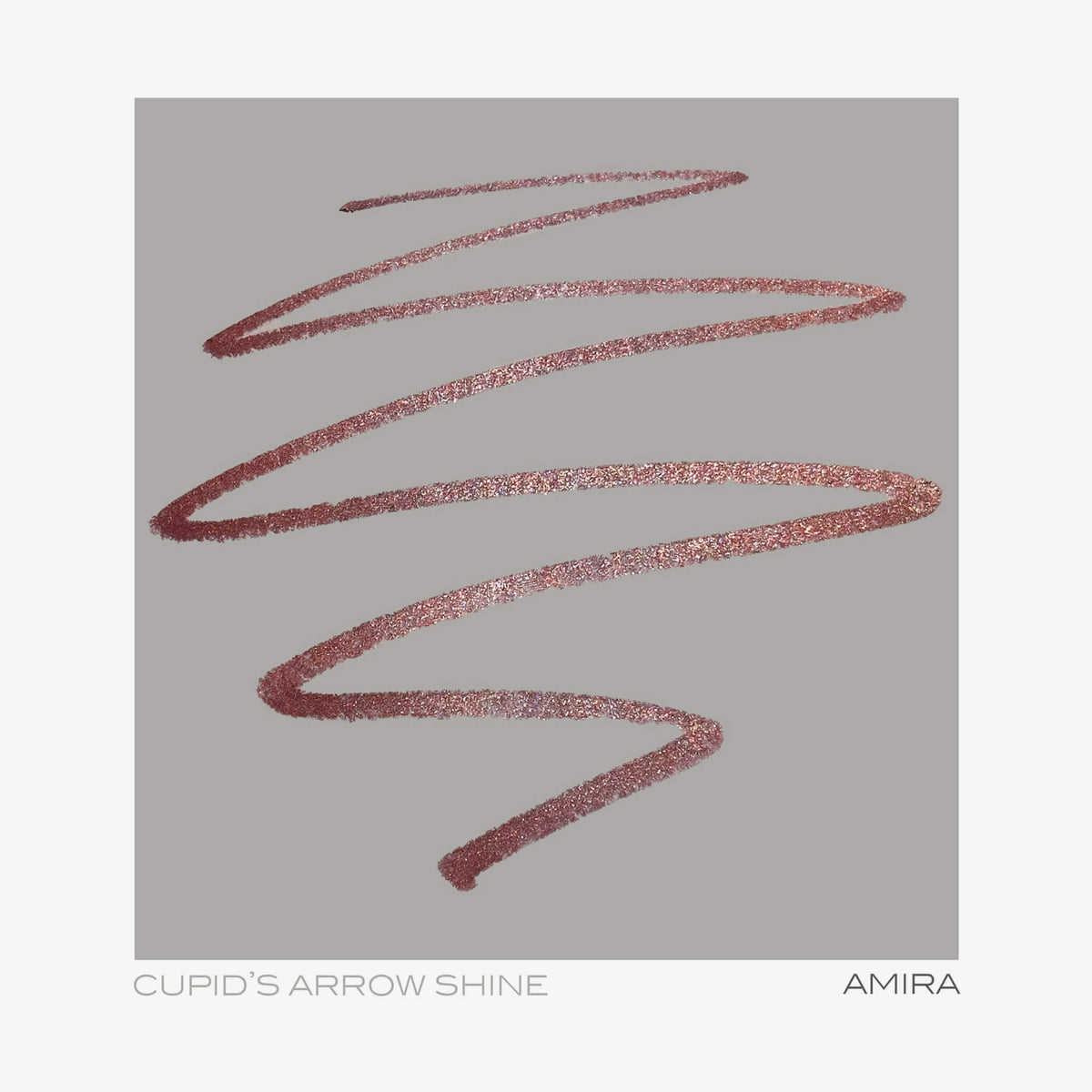 Ein schimmernder, roségoldener Cupid’s Arrow Longwear Stylo Arrow Shine wirbelt auf grauem Hintergrund. Text: CUPIDS ARROW SHINE AMIRA.