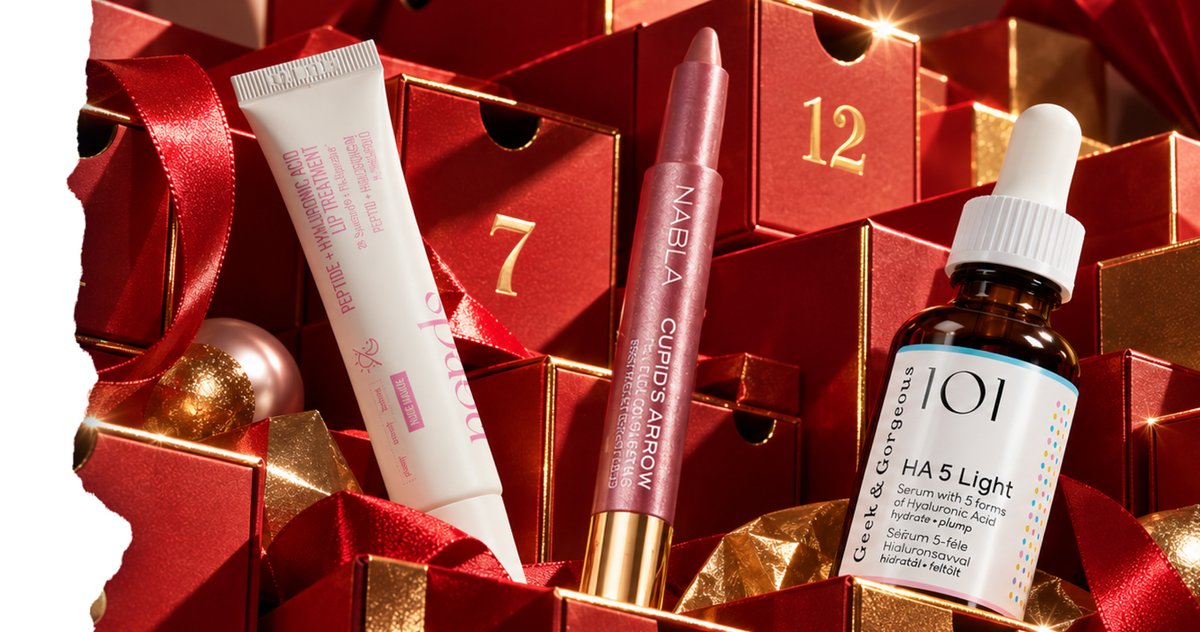 Eine Tube Lippenpflege, ein mauvefarbener Lippenstift und eine Flasche Gesichtsserum, angeordnet zwischen roten Geschenkboxen.