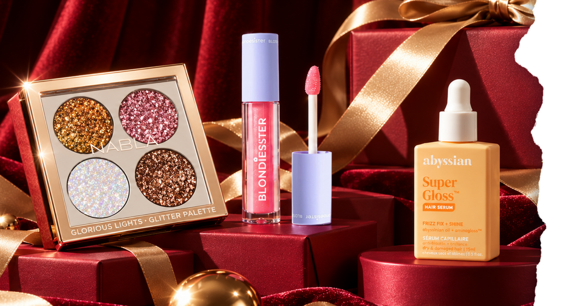 Die Nabla-Glitzer-Lidschattenpalette, der Blondiester-Lipgloss und das Abyssian-Haarserum, angerichtet auf Geschenkboxen mit Schleifen.