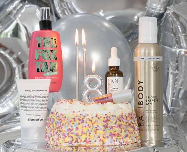 Beautyprodukte und Make-up vor silbernen Luftballons; in der Mitte eine bunte Torte mit Kerzen in Form einer 8 – zum 8. Geburtstag von paurish.com