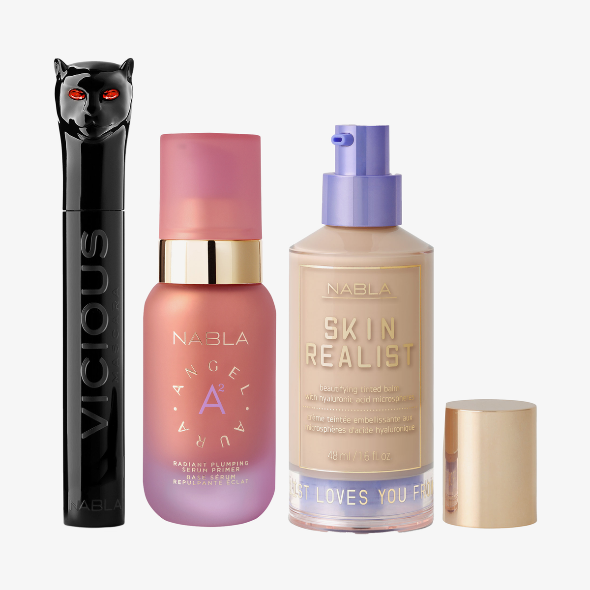 Drei NABLA-Produkte: schwarze Mascara mit Katzenkopf, rosa Angel Aura Serum-Primer und Skin Realist Tinted Balm in der Farbe 1.5 Light mit lilafarbenem Pumpspender.