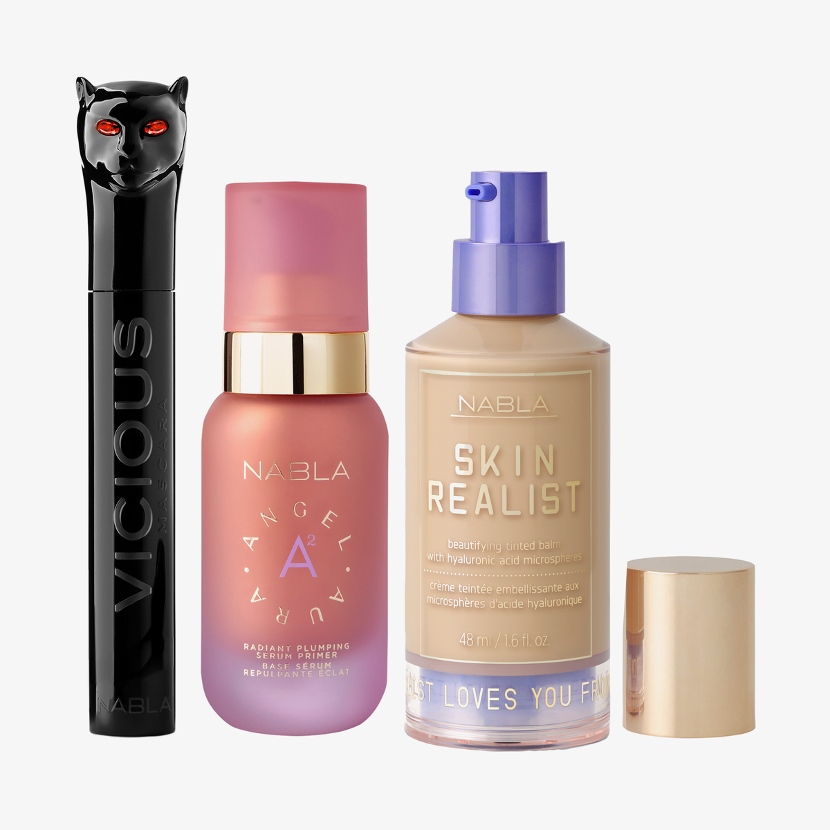 Drei NABLA-Produkte: schwarze Mascara mit Katzenkopf, rosa Angel Aura Serum-Primer und Skin Realist Tinted Balm in der Farbe 2 Light mit lilafarbenem Pumpspender.
