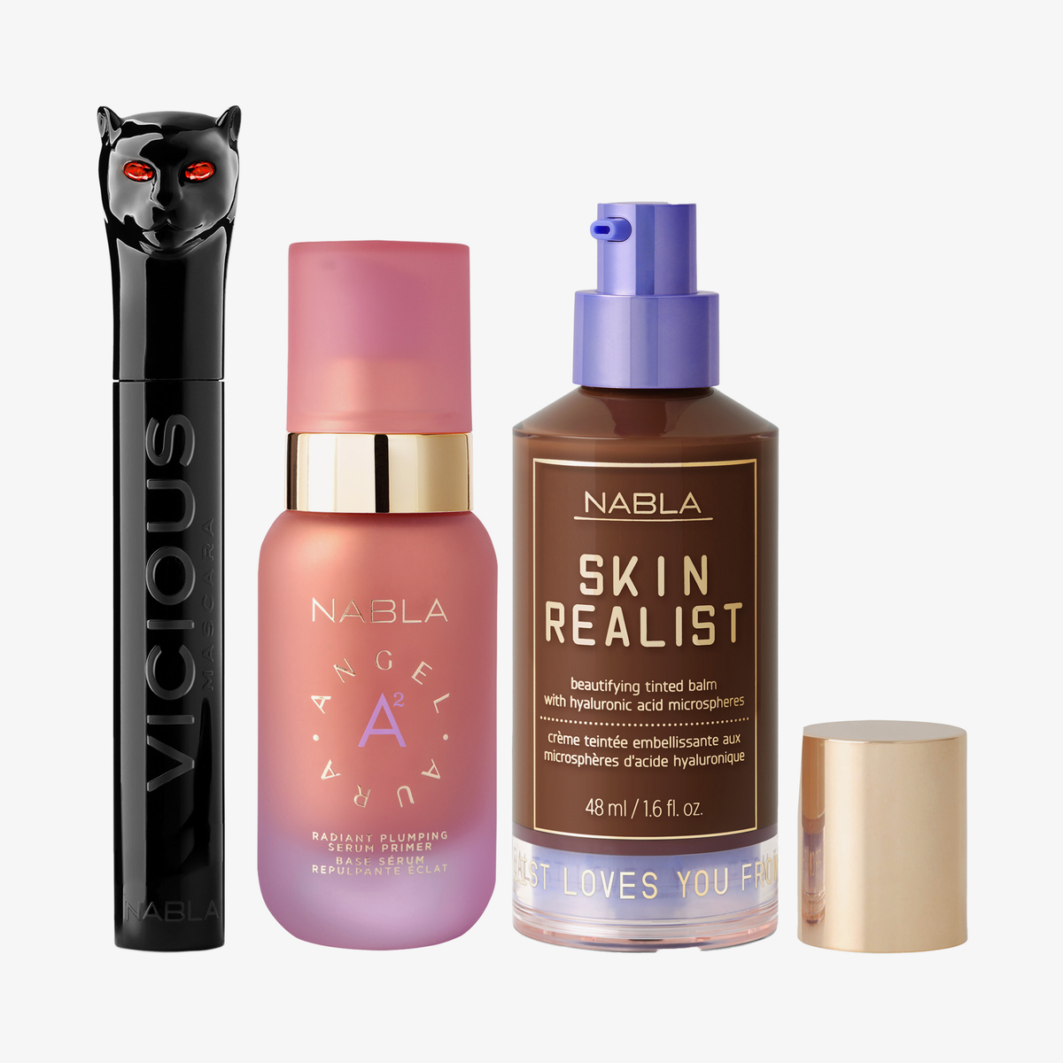 Drei NABLA-Produkte: schwarze Mascara mit Katzenkopf, rosa Angel Aura Serum-Primer und Skin Realist Tinted Balm in der Farbe 7 Deep mit lilafarbenem Pumpspender.