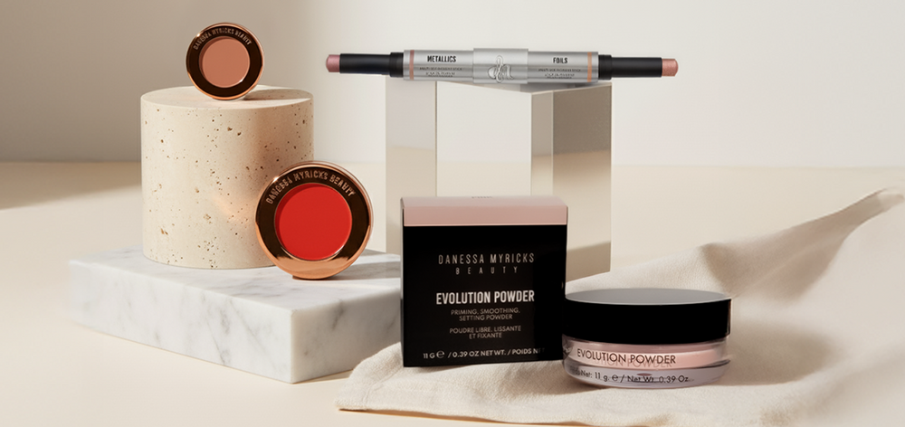 Danessa Myricks Produkte des Signature by Danessa Bundles dekorativ auf Podesten vor beigem Hintergrund.