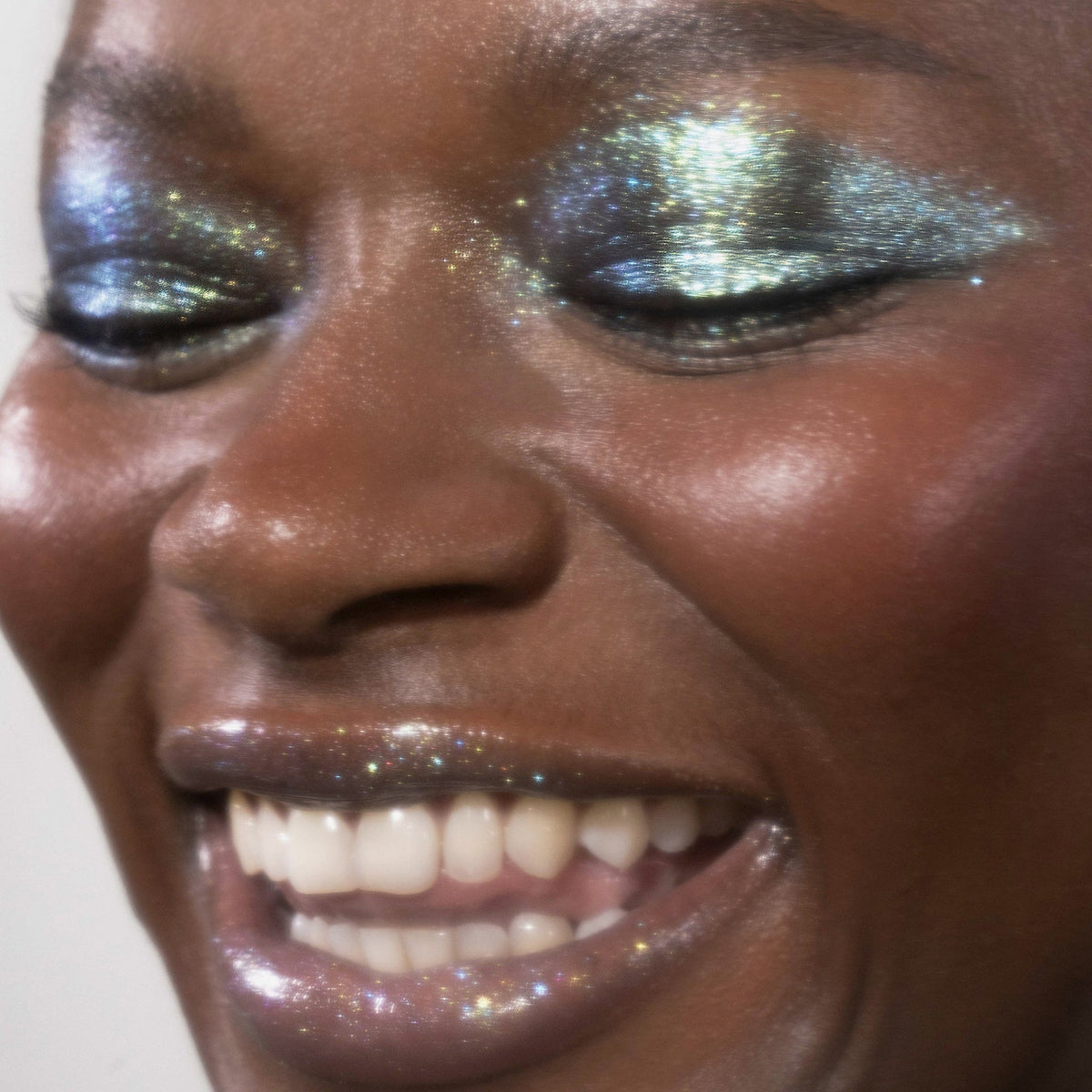 Nahaufnahme einer lächelnden Frau mit blau glitzerndem Lidschatten Sparkl Tease von LH Cosmetics.