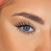 Nahaufnahme eines blauen Auges mit der Lash Out Mascara, langen definierten Wimpern und einer gepflegten Augenbraue.
