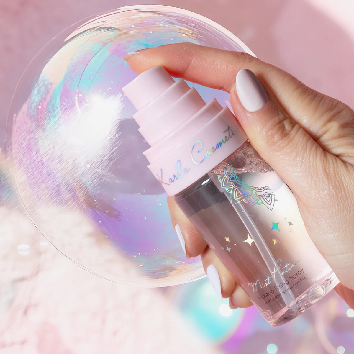 Eine Hand mit hellen Nägeln hält den Mist Potion – All-in-One Eyeshadow & Makeup Primer + Setting Mist neben einer großen schillernden Blase vor einem pastellfarbenen Hintergrund.