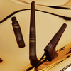 Zwei NABLA Freckle Maker-Stifte auf einem gold-braun reflektierenden Hintergrund, eine geöffnet.